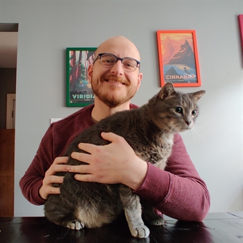 Dan Matthews smiling with an ambivalent cat